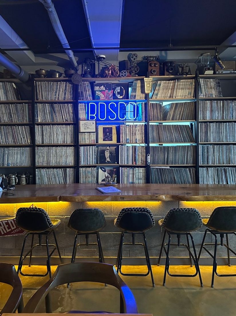 보스코 — 벽면 가득한 LP 아카이브와 파란 BOSCO 네온사인, 앞쪽 바 좌석