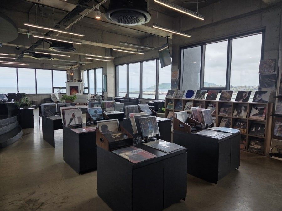 오아시스 제주 2층 LP 청음실 — 개별 턴테이블이 놓인 부스형 스테이션이 창을 따라 늘어서 있다