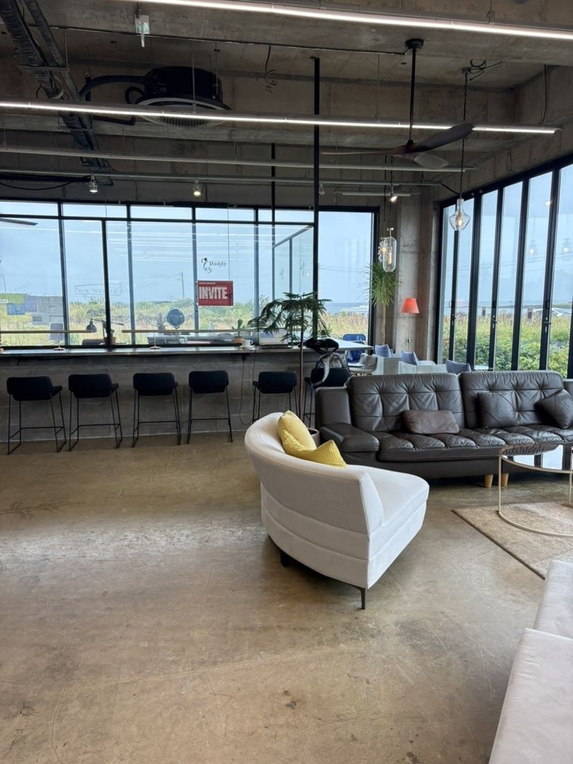 오아시스 제주 1층 — 넓은 소파와 창가 바 좌석이 있는 일반 카페 공간