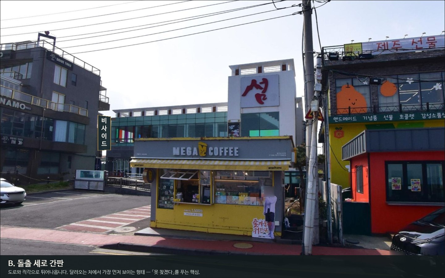 B안 — 건물 왼쪽 모서리에서 도로 쪽으로 직각 돌출한 세로 간판